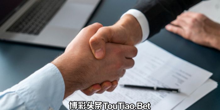 Two businessmen shake hands on top of signed documents, close up photo