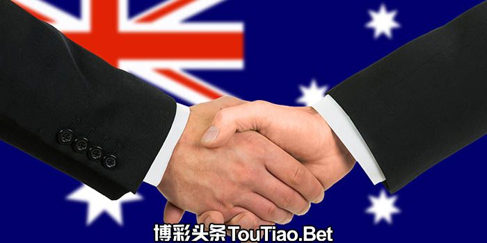 Two businessman shake hands before the flag of Australia